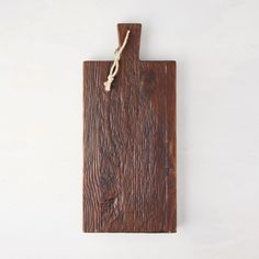 a wooden cutting board with rope hanging from it's side on a white wall