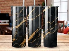 three black and gold vases sitting on top of a wooden table