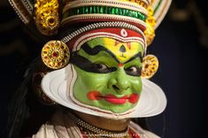 a close up of a person wearing a green mask and headdress on their face