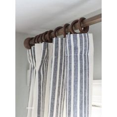 the curtain is hanging on the rod in the room with white and blue striped curtains