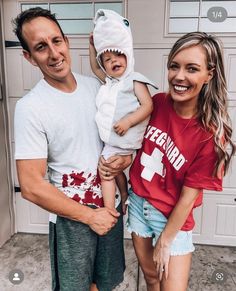 a man and woman holding a baby in front of a garage door