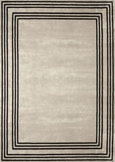 an area rug with black and white lines on the border, in front of a beige background