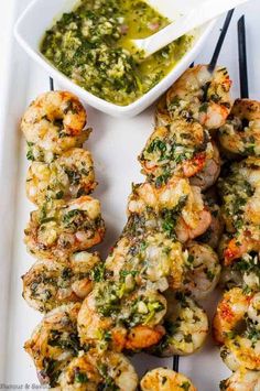 grilled shrimp skewers on a plate with dipping sauce