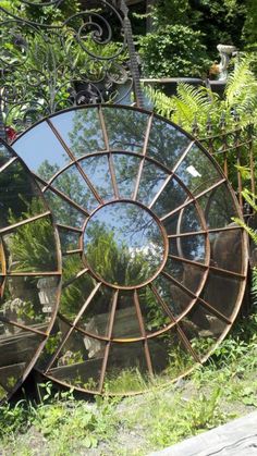 a large mirror sitting on top of a lush green field