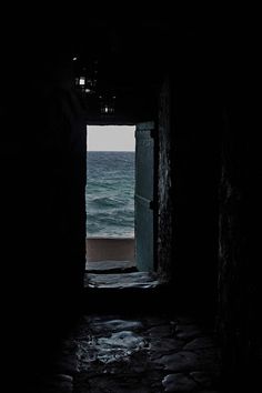 an open door leading to the ocean with light coming in from it and water on either side