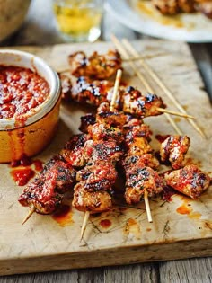 chicken skewers with marinara sauce and toothpicks on a cutting board