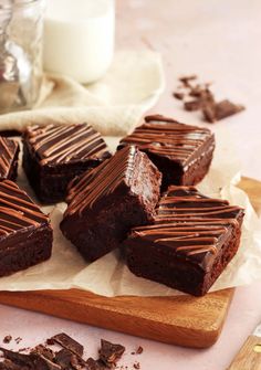 chocolate brownies are on a cutting board next to a glass of milk