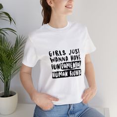 Stand up for your beliefs and show your support for fundamental human rights with our "Girls Just Wanna Have Fundamental Human Rights" unisex jersey short sleeve tee. Crafted with soft and durable cotton, this classic fitted shirt will quickly become your go-to favorite. Ribbed knit collars provide a comfortable and flattering fit, while tapered shoulders ensure it stays looking great wear after wear. With dual side seams to maintain its shape, this tee is perfect for both everyday wear and acti Empowering Cotton Tops With Letter Print, Empowering Short Sleeve Tops With Letter Print, Empowering Cotton T-shirt With Graphic Print, Empowering Text Print Crew Neck T-shirt, Women’s Rights Shirt, Empowering Graphic Cotton T-shirt, Organic Cotton Slogan T-shirt Short Sleeve, Feminist Tee Shirts, Empowering Short Sleeve T-shirt With Text Print