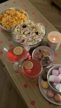 a table topped with bowls filled with candy and marshmallows next to candles