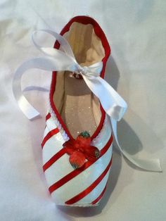 a pair of red and white striped shoes with a bow on the side, sitting on a bed