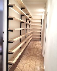 an empty walk in closet with shelving and wood flooring on the side wall