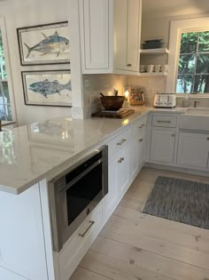 a kitchen with white cabinets and marble counter tops