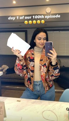 a woman taking a selfie with her cell phone in front of a counter top