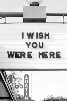 a sign that says i wish you were here on the side of a building in black and white