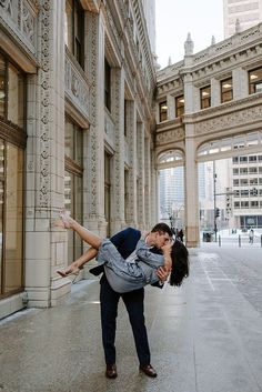 a man and woman kissing on the street in front of an old building with arches