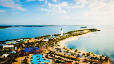 an aerial view of a beach resort with a lighthouse in the distance and blue water