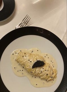 a black and white plate topped with food on top of a table next to silverware