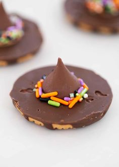 chocolate covered cookies with colorful sprinkles and a small cone on the top