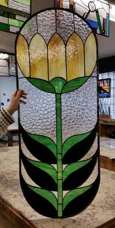 a stained glass flower is being displayed in a shop window with other items on the shelves behind it