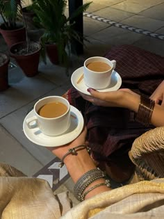 two cups of coffee sitting on top of each other in front of a woman's legs