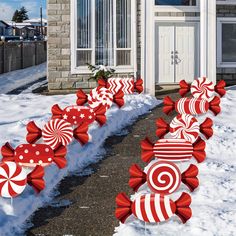 red and white candy canes are lined up in front of a house with snow on the ground