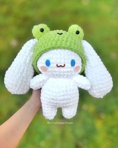 a crocheted frog is held up by someone's hand