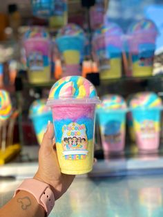 a person holding up a cup with ice cream on it in front of other cups