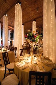 the tables are set up for an event with white linens and lights on them