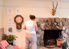 a woman standing in front of a stone fireplace