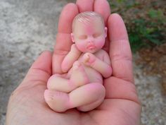 a hand holding a small baby doll in it's palm