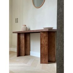 a wooden table with two vases on top of it next to a white wall