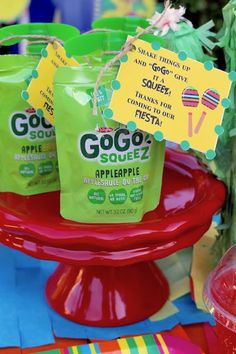 three bags of gogo squeezez are sitting on a red plate with a cactus in the background