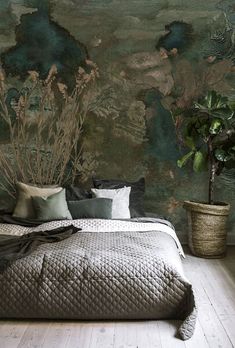 a large bed sitting next to a potted plant on top of a wooden floor