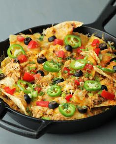 a skillet filled with chicken, peppers and black olives