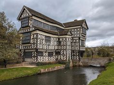 an old building with black and white paint next to a river