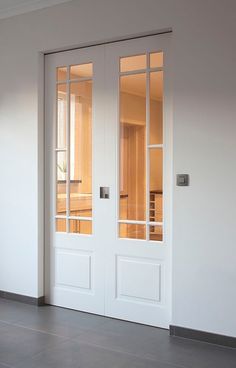 an empty room with two white doors and no one sitting in the chair next to it