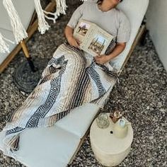 a young boy laying in a chair reading a book