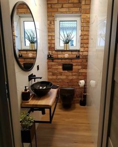 a bathroom with a sink, mirror and toilet in it's stall area next to a brick wall