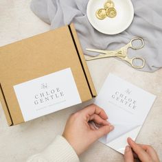 a person is holding some paper and scissors in front of a box with two cards