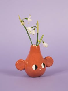 a small vase with flowers in it on a purple background, the bottom half is shaped like an elephant's head