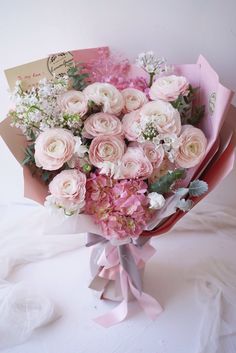 a bouquet of pink and white flowers on top of a table next to a card