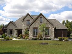 a large brick house sitting in the middle of a lush green field next to a tree