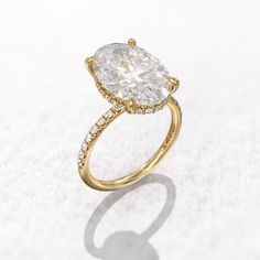 a gold ring with a pear shaped diamond in the center, on a white surface