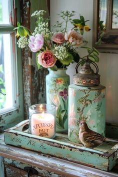 two vases with flowers and candles sit on a table in front of a window