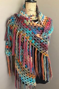 a multicolored crocheted shawl on a mannequin