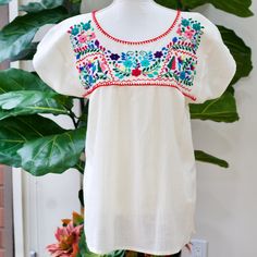 "The Yucatan embroidered top is beautifully made in Merida Yucatan, Mexico, each piece is  fully hand embroidery. Details: Size S/M - measurements: Bust: 40\" - 27.5\" length(shoulder to bottom Hem) - Cotton  thread Embroidered - Material: 100% Cotton - split sides - All items are shipped from the US All Mi Mundo Mexicano  items are 100% handmade by artisans in Mexico. Each stitch and item is completely unique and one-of-a-kind, so you'll never find two that are exactly the same! All  items may vary slightly in size, color, and design - that's what makes handmade items so special and charming!  Your Purchase supports artisans craft and families ." Folk Style Floral Embroidered Dress For Ceremonies, Festival Embroidered Multicolor Top, Festive Traditional Top With Floral Embroidery, Folk Style Floral Embroidered Dress For Festivals, Festive Tops With Intricate Embroidery And Short Sleeves, Traditional Tops With Floral Embroidery For Festive Occasions, Traditional Tops With Intricate Embroidery For Festivals, Traditional Floral Embroidered Dress For Fiesta, Short Sleeve Floral Embroidered Festive Dress