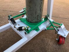 an electric device attached to a pole on the ground next to a street with red wheels