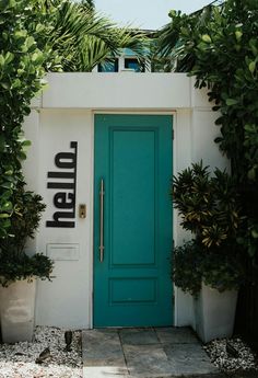 a blue door with the word hello written on it in front of some potted plants