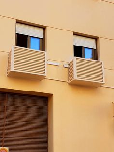 two balconies on the side of a building with shutters open to let in light