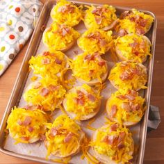 a tray filled with mini pizzas covered in cheese and bacon on top of a wooden table